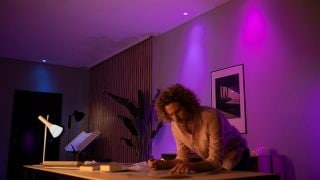Pametna LED svjetla Philips Hue stvaraju živopisni ljubičasti i ružičasti atmosferu u dnevnom boravku, prikazujući prilagodljivo osvjetljenje za filmske večeri i opuštanje u modernim domovima.